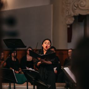 Mariela Flores in a black dress sings passionately